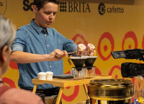A person holding a spoon over a coffee makerAI-generated content may be incorrect.